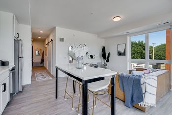 a dining area with a white table and chairs and a kitchen with a large window